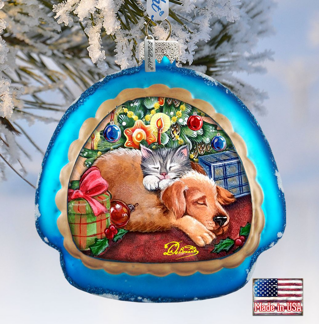 A blue ornament with a picture of a cat and a dog sleeping together, surrounded by Christmas decorations and gifts.