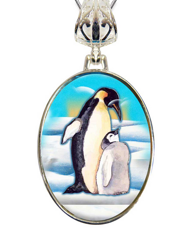 A pendant featuring a painting of two penguins, one larger and one smaller, standing together in a snowy landscape.