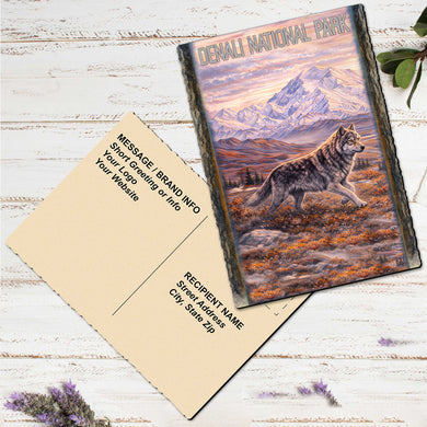 a postcard with a wolf on it, placed on a white wooden surface.