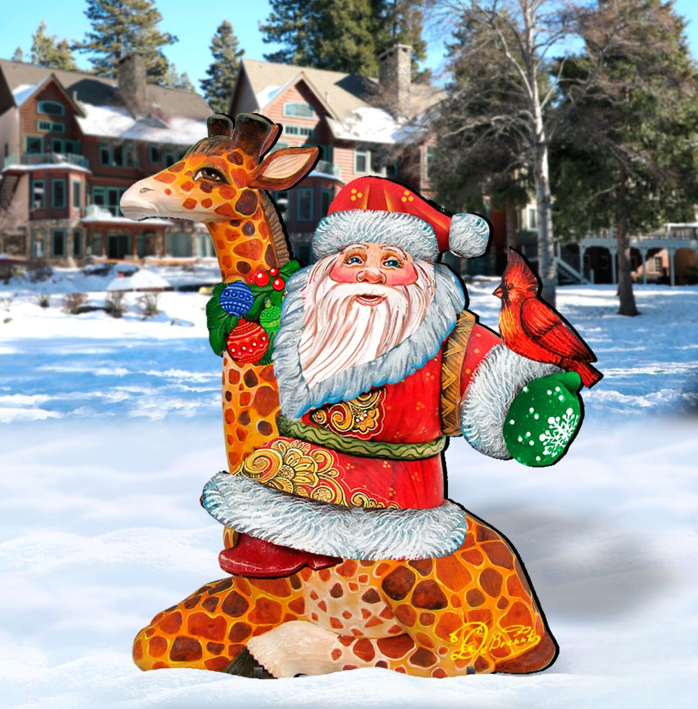 A colorful, hand-painted cardboard cutout of Santa Claus holding a bird and a toy car, standing in the snow with a house in the background.