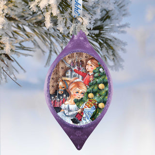 A purple ornament with a Christmas tree and two girls in the center, surrounded by snow.