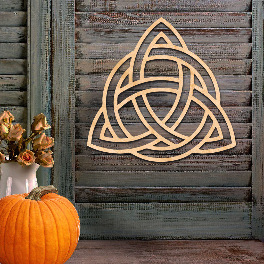 a wooden wall with a carved Celtic knot design, a vase of dried roses, and a pumpkin.