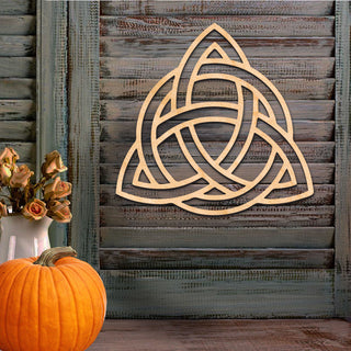 a wooden wall with a carved Celtic knot design, a vase of dried roses, and a pumpkin.