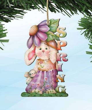A colorful ornament featuring a bunny wearing a hat and dress, with a flower on its head, and the word 