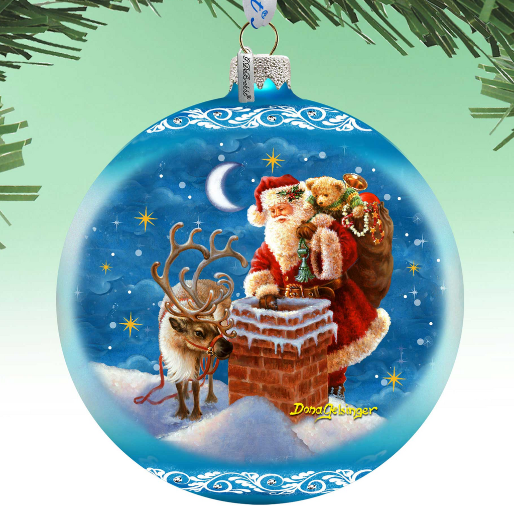 A blue Christmas ornament with a painting of Santa Claus riding a reindeer on a snowy mountain, with a crescent moon and stars in the night sky.