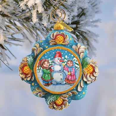 A colorful ornament featuring a snowman, two children, and a snowy landscape, hanging from a tree branch.