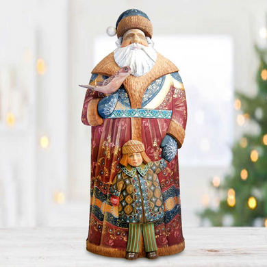 A colorful figurine of Santa Claus holding a bird, with a smaller figure of a child in his lap, set against a blurred background with Christmas lights.