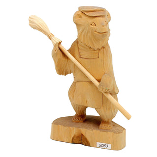 A wooden carving of a bear holding a broom.