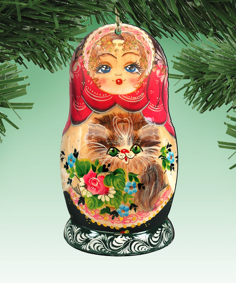 A colorful, intricately painted nesting doll ornament with a cat design, hanging on a tree branch.