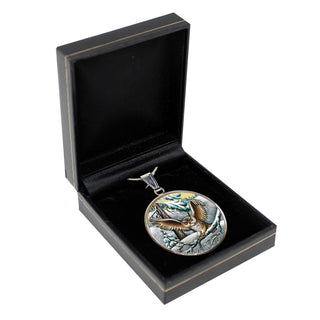 A round pendant with an eagle design is displayed in a black jewelry box.