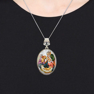 A silver necklace with a pendant featuring a religious scene.