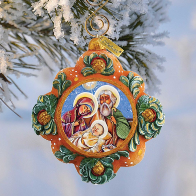 A decorative ornament hanging from a tree branch, featuring a religious scene with the Virgin Mary, baby Jesus, and the saints.
