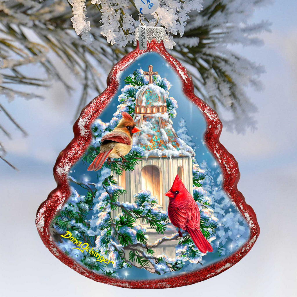 A Christmas ornament shaped like a birdhouse, featuring two red cardinals perched on the roof.