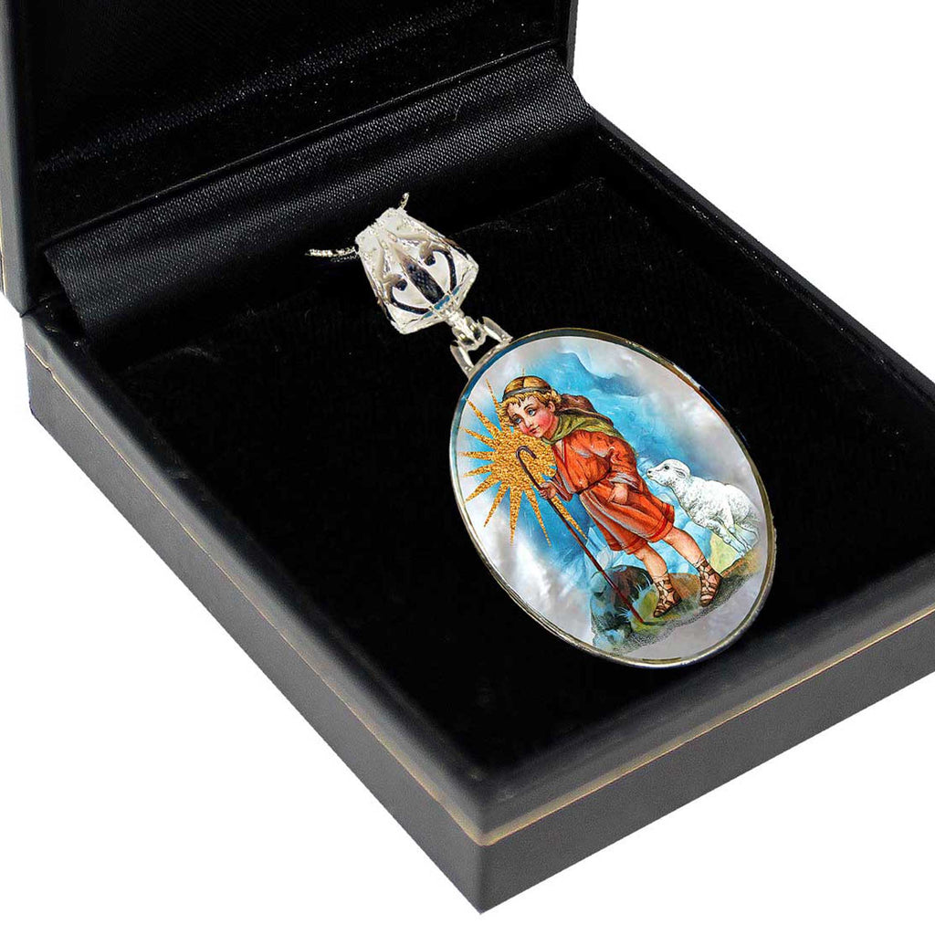 A pendant with a religious figure, possibly a saint or deity, is displayed in a black jewelry box.