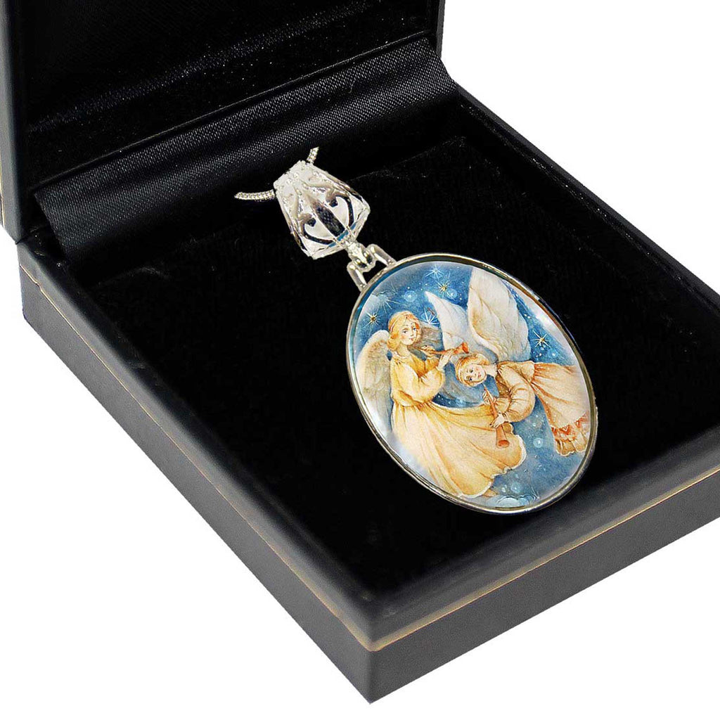 A pendant with a painting of angels is displayed in a black jewelry box.