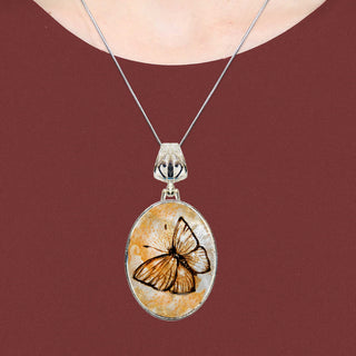 A silver necklace with a circular pendant featuring a butterfly design.