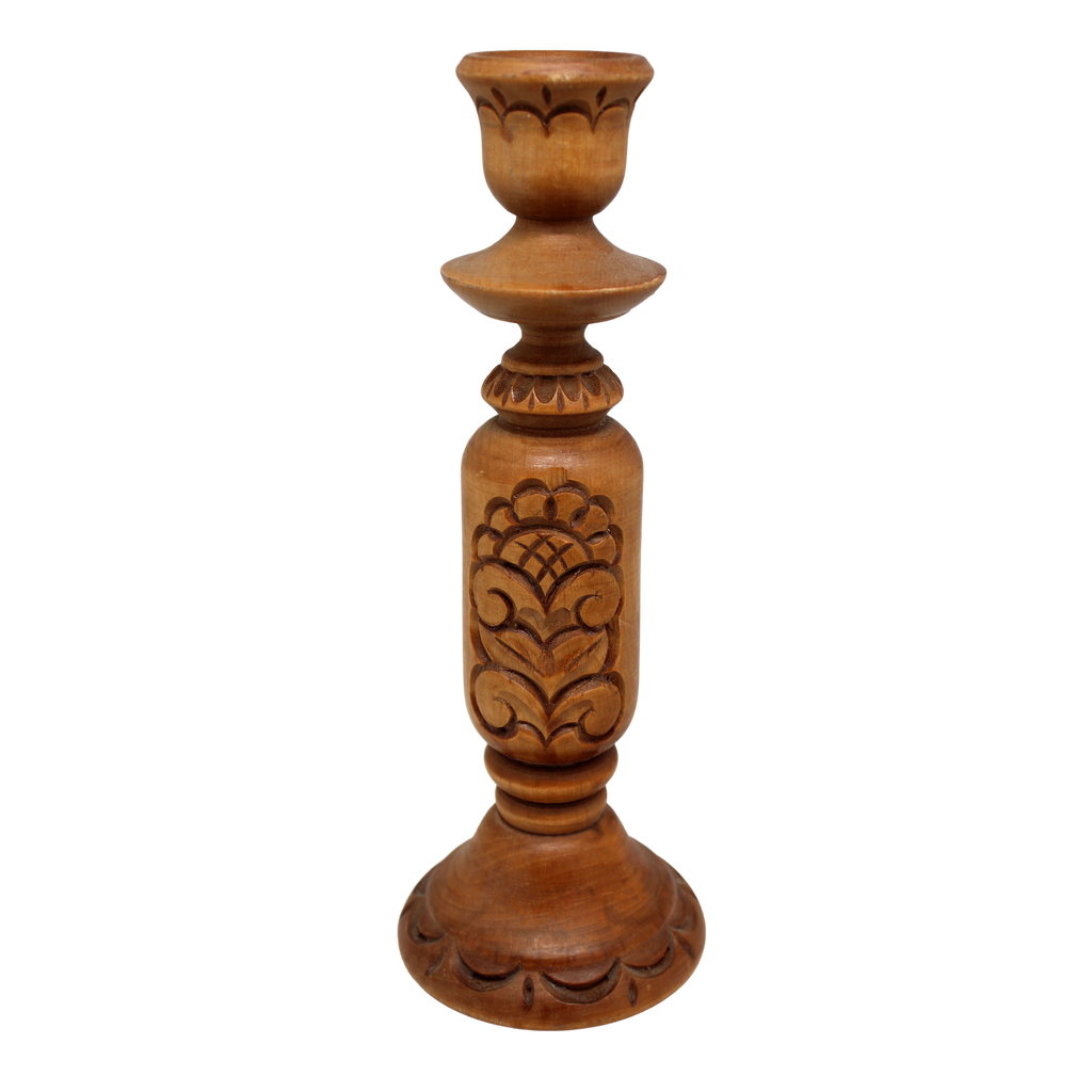 A wooden candle holder with a carved design on the front.
