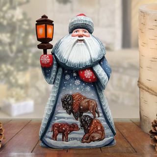 A wooden Santa Claus figurine holding a lantern and surrounded by animals, including bison, on a snowy background.