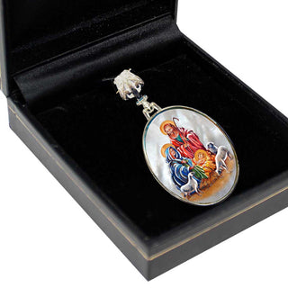 A black jewelry box containing a decorative pendant with a religious scene on it.