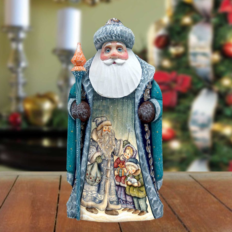 A figurine of Santa Claus holding a staff and surrounded by children, set against a blurred Christmas tree background.