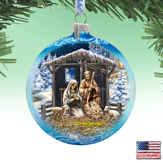 A blue Christmas ornament depicting the nativity scene with the baby Jesus, Mary, and Joseph in a manger, surrounded by animals and a snowy landscape.