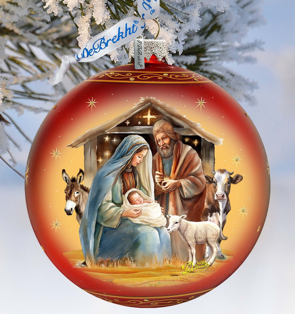 A red Christmas ornament with a nativity scene depicting the Holy Family of Jesus, Mary, and Joseph, along with animals such as a donkey and a sheep.