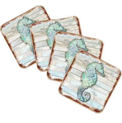 four square coasters with a seahorse design on them.