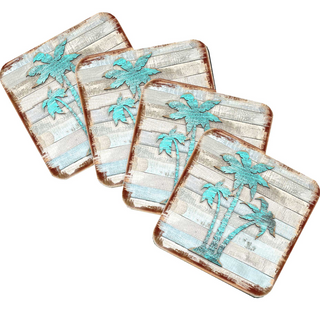 four square coasters with a tropical theme, featuring palm trees and other natural elements. The coasters have a distressed, weathered appearance, giving them a vintage, rustic look.