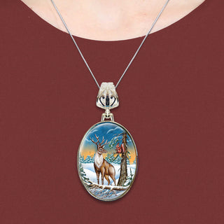 A necklace with a pendant featuring a deer standing in a snowy forest scene.