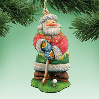 A colorful ornament of Santa Claus holding a golf club, hanging from a tree branch.
