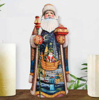 A colorful, hand-painted Santa Claus figurine stands on a wooden surface, holding a lantern and a small box.