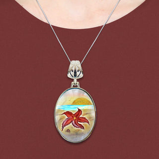 A necklace with a pendant featuring a colorful image of a red starfish against a beach scene.