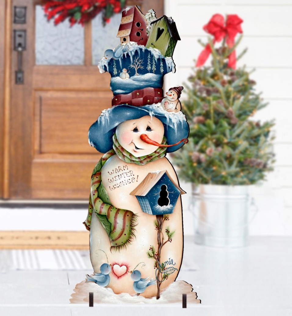 A snowman figure with a birdhouse and a wreath stands in front of a door, with a Christmas tree visible in the background.