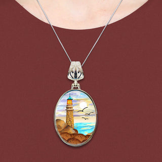A necklace with a pendant featuring a lighthouse and a seascape.