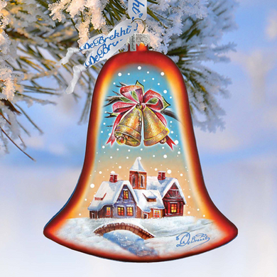 A red and gold bell ornament with a winter village scene and bells hanging from a tree branch against a snowy background.