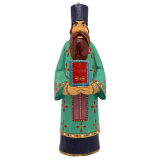 A colorful wooden statue of a bearded man wearing a green robe with red and gold accents, holding a book and standing against a white background.
