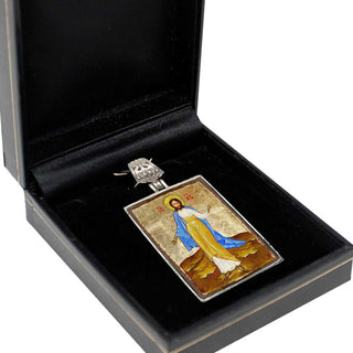 a pendant or charm in a black box, which appears to be a religious or symbolic piece.