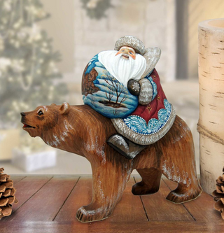 A wooden bear statue dressed as Santa Claus, with a white beard and hat, is sitting on top of the bear.