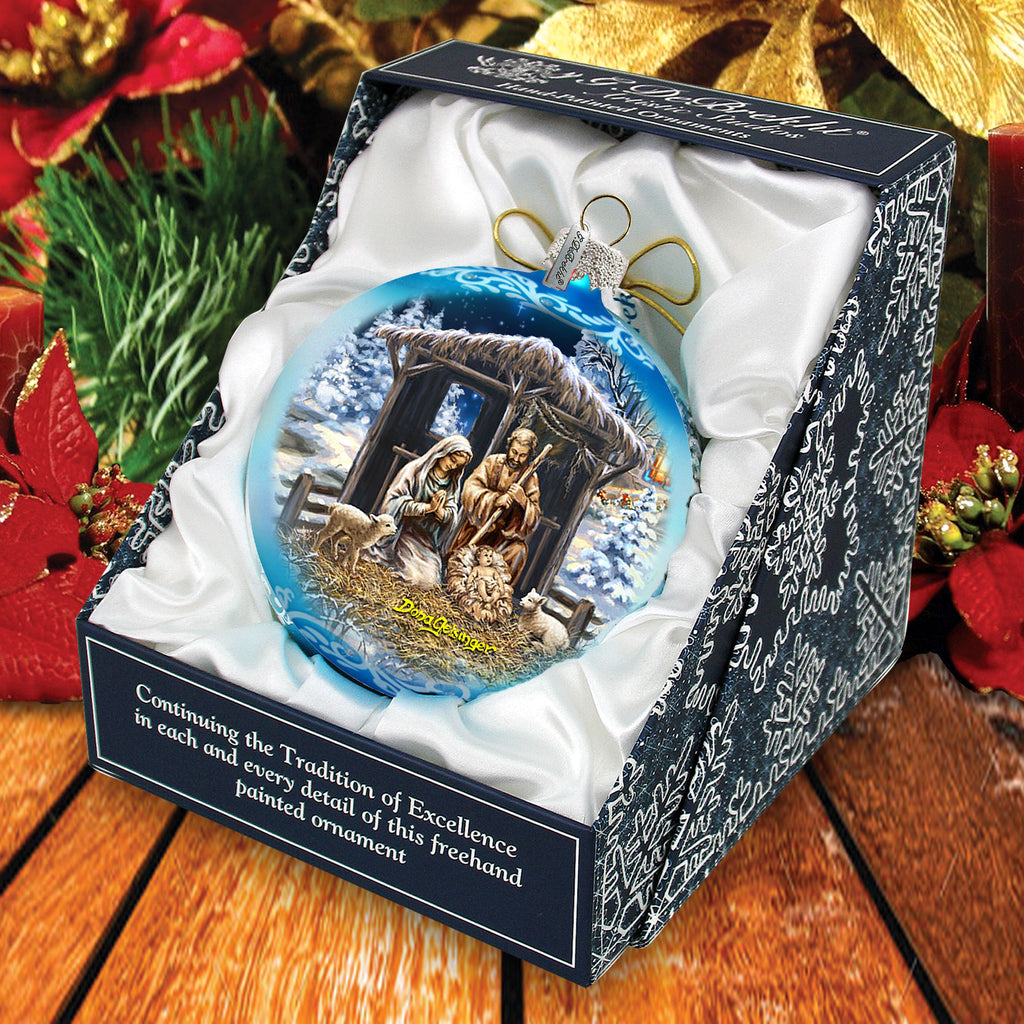 A blue and white ornament in a box, depicting a nativity scene with a man, woman, and baby in a stable.