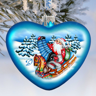 A heart-shaped ornament with a painted illustration of Santa Claus riding a sleigh pulled by a reindeer, set against a snowy winter landscape with pine trees.