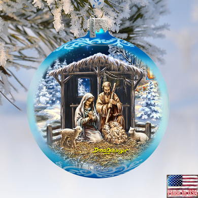 A blue Christmas ornament depicting the nativity scene with the Virgin Mary, baby Jesus, and the saints in a snowy landscape.