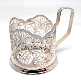a silver cup with a handle on a white surface