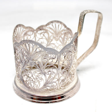 a silver cup with a handle on a white surface
