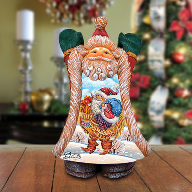 A wooden figurine of Santa Claus holding a rooster and a bag, with a snowy landscape in the background.