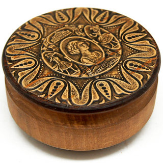 a round wooden box with an intricate engraved design on its lid.
