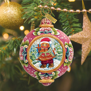 A pink ornament with a Christmas tree and a gold star ornament in the background.