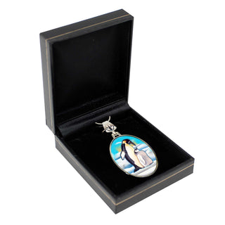 A black jewelry box containing a silver pendant with a penguin design.