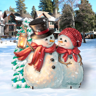 A snowman and a snowman standing together in a snowy landscape, with a house and trees in the background.
