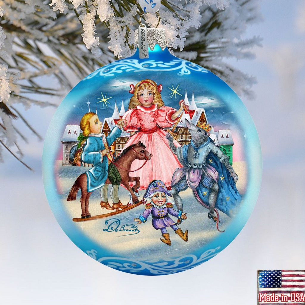 A blue Christmas ornament with a painting of a girl in a pink dress surrounded by various characters, including a horse, a dragon, and other fantastical elements, set against a snowy landscape.