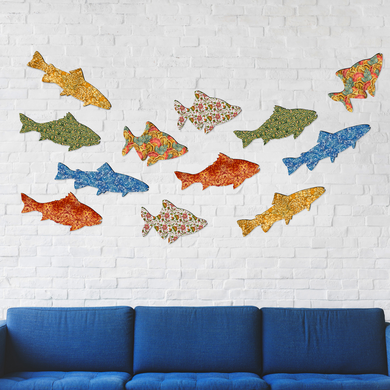 a blue couch against a white brick wall, with a collection of colorful fish-shaped cutouts displayed on the wall.